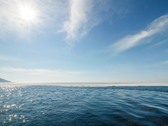 Large angle de vue sur la mer avec le soleil qui se reflète et un voile de nuages
